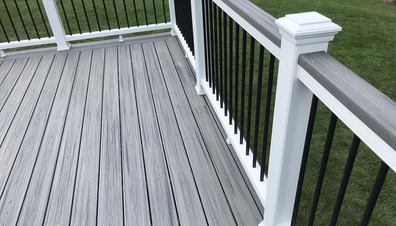 Deck in New Hudson, MI., constructed out of Trex Transcend Tropical decking in Island Mist and complimented by Classic White Trex railing with black balusters and Classic White privacy wall.
