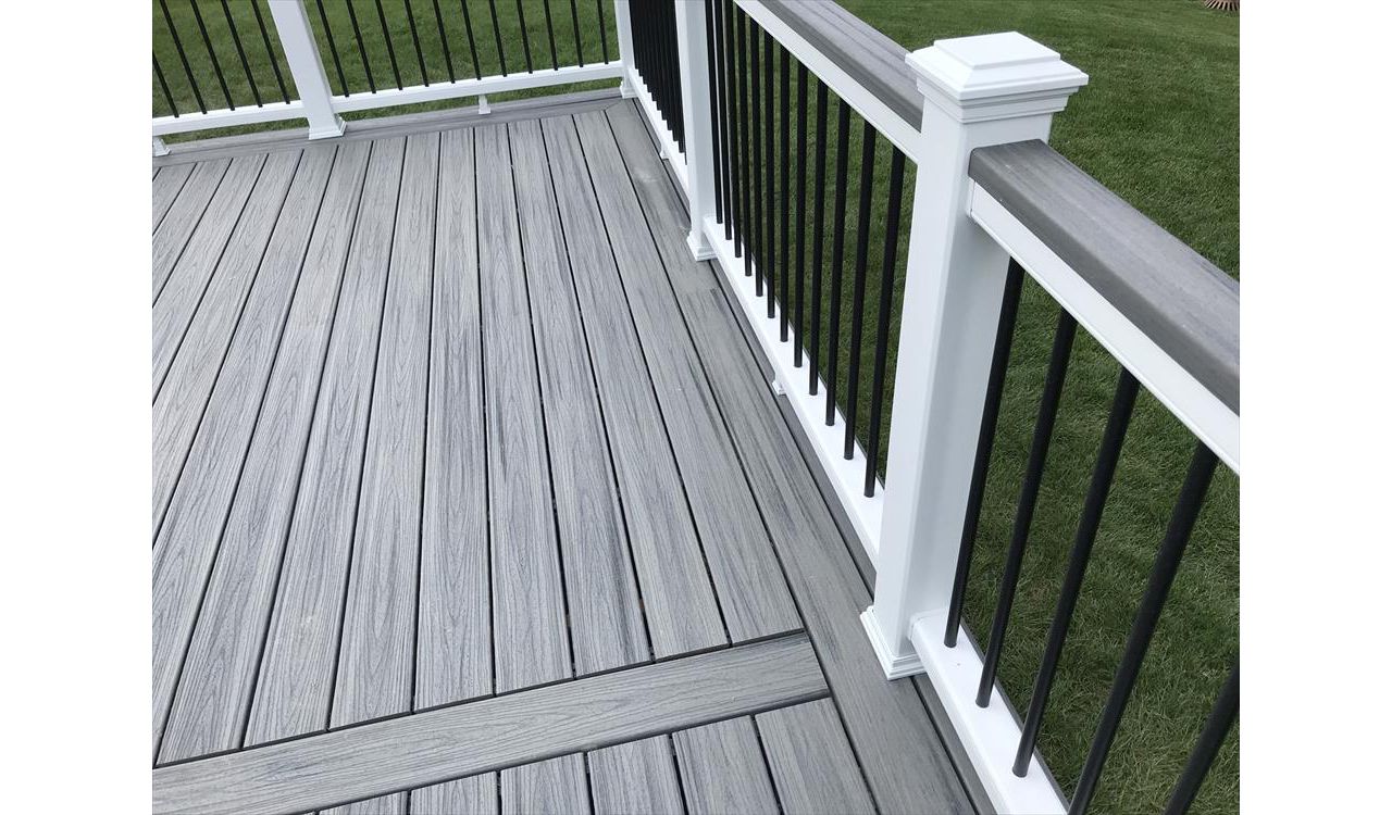 Deck in New Hudson, MI., constructed out of Trex Transcend Tropical decking in Island Mist and complimented by Classic White Trex railing with black balusters and Classic White privacy wall.