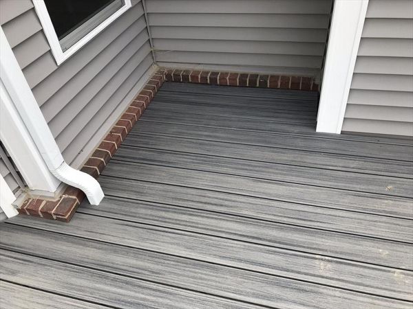 Deck in New Hudson, MI., constructed out of Trex Transcend Tropical decking in Island Mist and complimented by Classic White Trex railing with black balusters and Classic White privacy wall.
