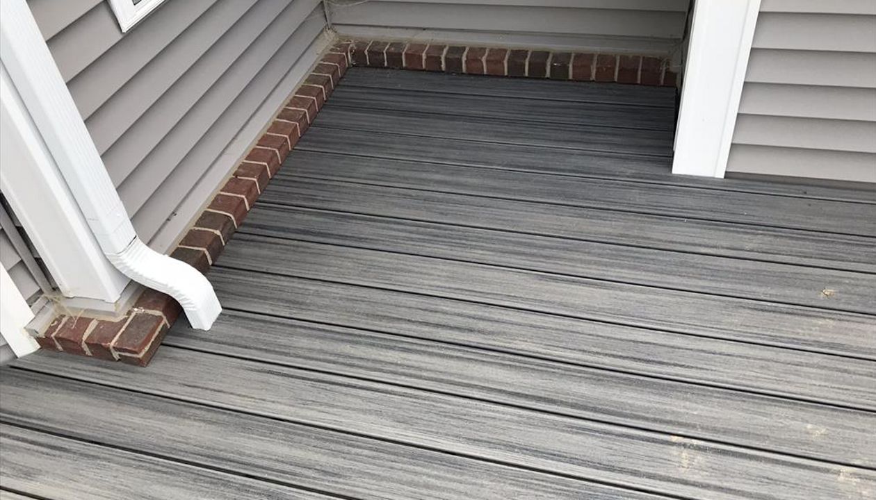 Deck in New Hudson, MI., constructed out of Trex Transcend Tropical decking in Island Mist and complimented by Classic White Trex railing with black balusters and Classic White privacy wall.