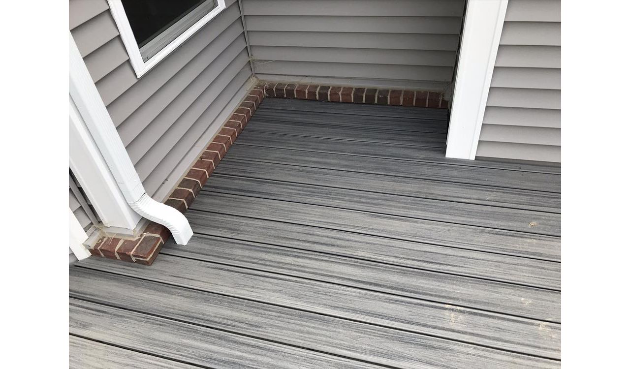 Deck in New Hudson, MI., constructed out of Trex Transcend Tropical decking in Island Mist and complimented by Classic White Trex railing with black balusters and Classic White privacy wall.