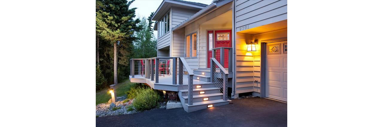 Lighting highlights this Trex and CableRail front porch.