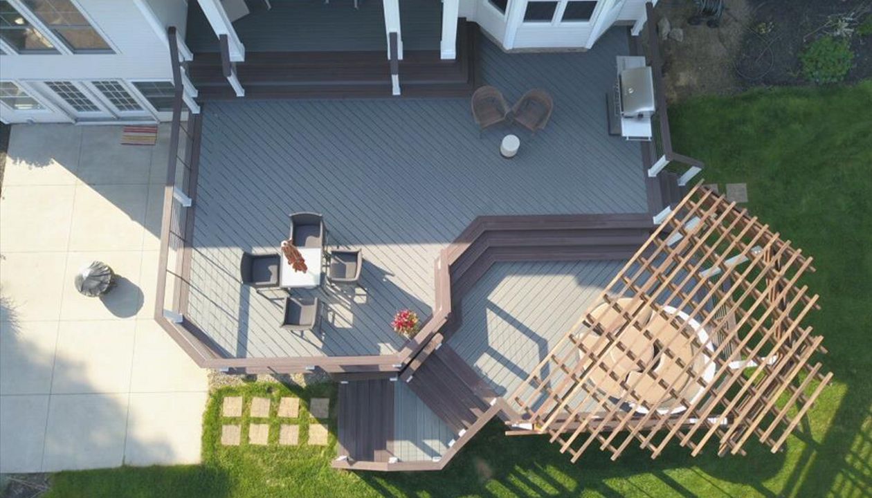 Trex Enhance Clamshell deck featuring Trex Vintage Lantern boarder, fascia, and cocktail rail. Custom Cedar pergola