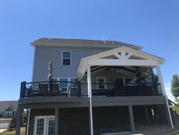 Partially covered curved Pebble Gray deck. Stone veneer gas fireplace completes this outdoor living space