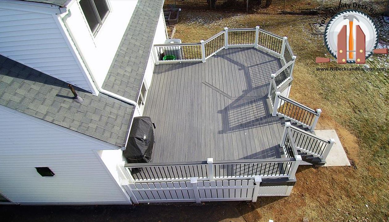 Custom designed deck in Nutley, NJ with an octagon on one corner. This deck is Trex Transcend Island Mist decking with Trex Transcend white railings and black square aluminum balusters. There is also an Island Mist cocktail rail.