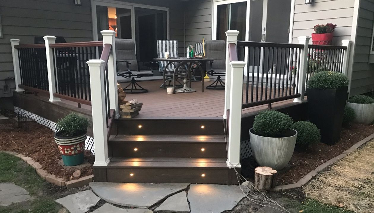 Trex Transcend Lava Rock border with Enhance Naturals Toasted Sand field boards. Trex Transcend railing installed using aluminum posts instead of embedded 4x4 lumber for increased durability and strength. Overall a beautiful backyard transformation!