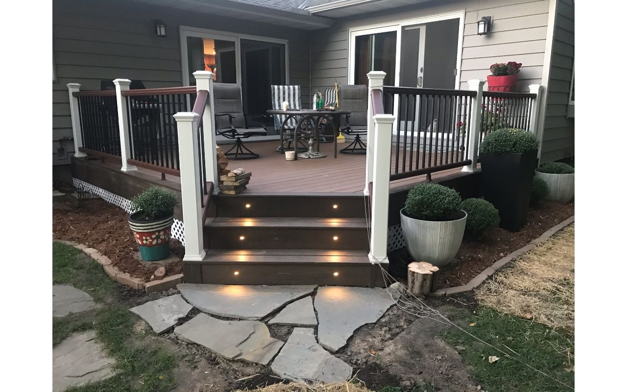 Trex Transcend Lava Rock border with Enhance Naturals Toasted Sand field boards. Trex Transcend railing installed using aluminum posts instead of embedded 4x4 lumber for increased durability and strength. Overall a beautiful backyard transformation!