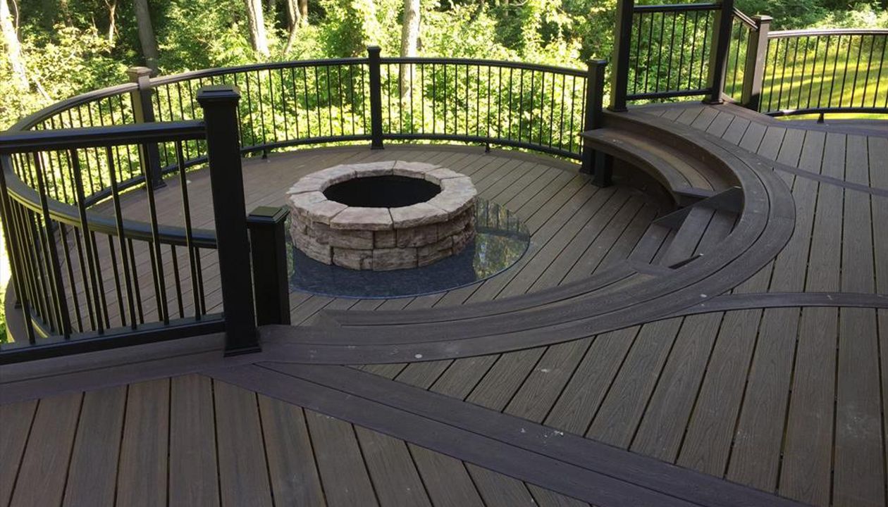 This custom Trex deck has a custom curved seating area along with a custom firepit to keep you warm on those cool summer nights. This deck has Trex transcends havana gold decking and a custom curved vintage lantern rail.