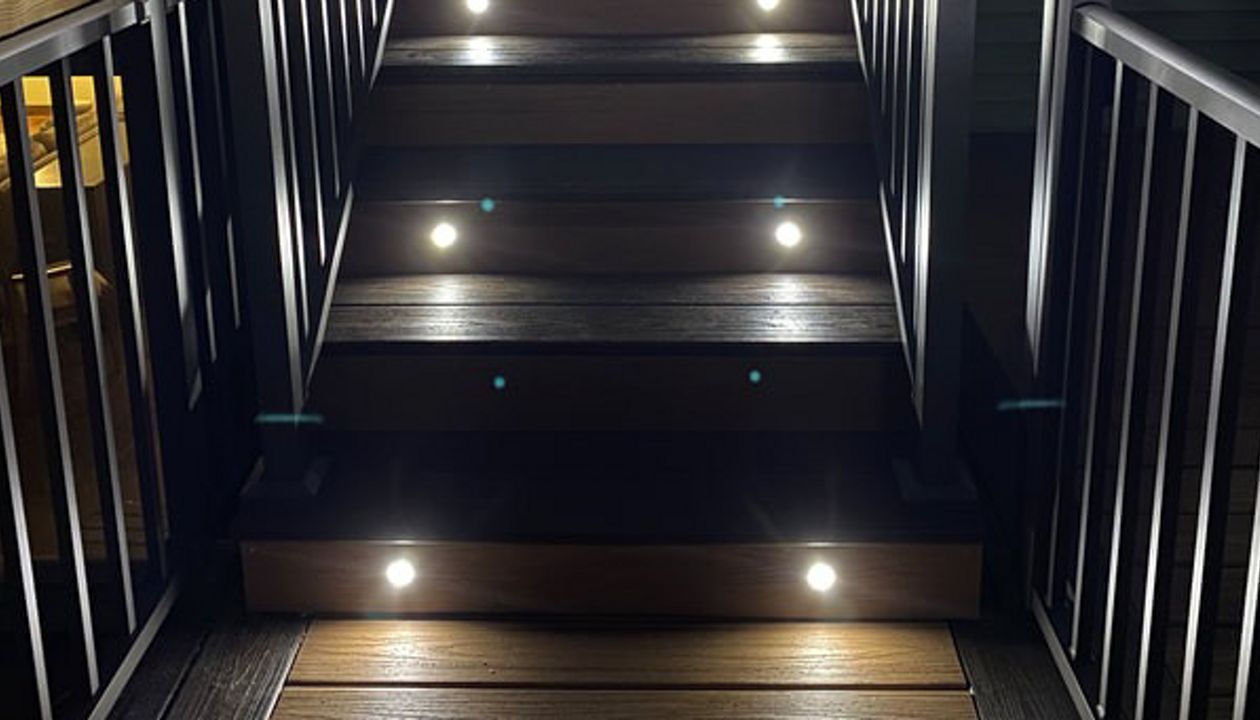 Two-Tone Low-Maintenance Trex Transcend Composite Deck Stairway with Aluminum Railing & Gate and Super Cool LED Lighting for Safety and Ambiance in the Rochester, MN Area built by Schmidt Carpentry, LLC
