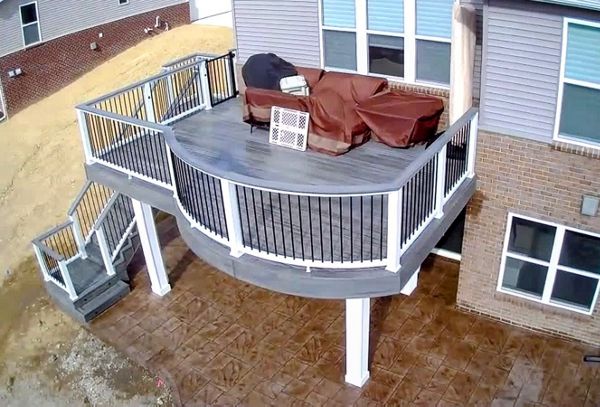 Custom curved deck with rain escape system and stamped concrete patio below
