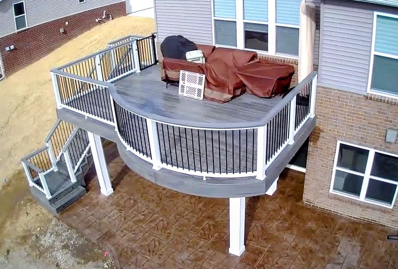 Custom curved deck with rain escape system and stamped concrete patio below