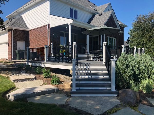 Large TREX Island Mist deck with Black Signature rail, White Transcends post, cap, skirt, and fascia with elevated covered porch