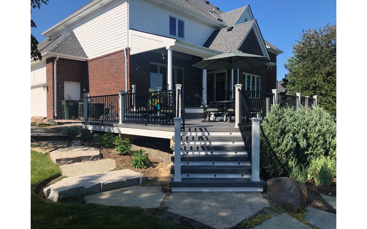 Large TREX Island Mist deck with Black Signature rail, White Transcends post, cap, skirt, and fascia with elevated covered porch