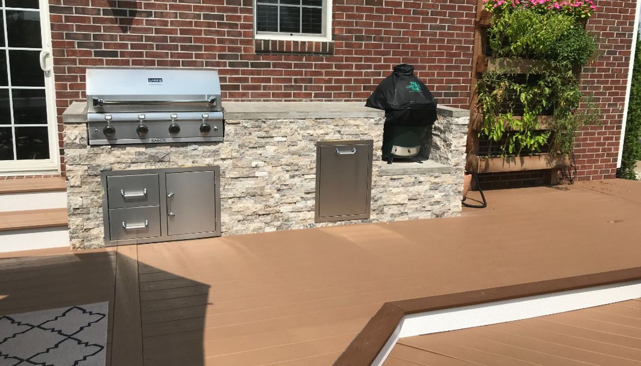 Trex Deck (Beach Dune) with Bullnose Border (Saddle) and Parting Board (Beach Dune). Outdoor Kitchen with Faux stone Façade and Concrete Top.