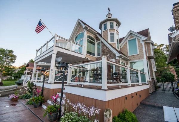 Lake house deck featuring Trex Enhance Beach Dune decking with white Trex Transcend universal railing with tempered glass. This 2-story deck has a drainage system along with a custom spiral staircase. Skirting and Post wraps give an elegant touch.