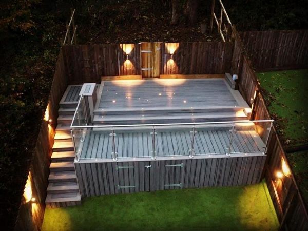 Trex Transcend balcony Island Mist field with Gravel path boarder , Stainless steel and glass railing and Trex RainEscape deck drainage system for dry storage . Swansea