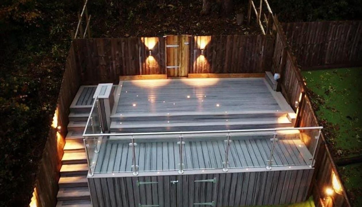 Trex Transcend balcony Island Mist field with Gravel path boarder , Stainless steel and glass railing and Trex RainEscape deck drainage system for dry storage . Swansea