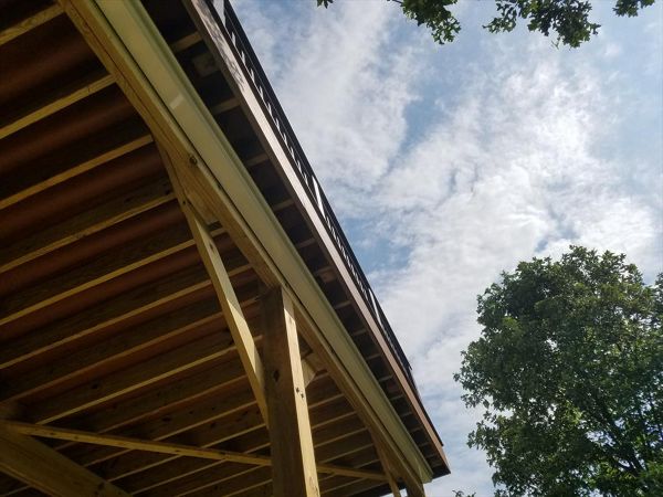 Trex RainEscape System with an open ceiling. The channels have a red/brown color and can be seen from underneath the deck.
