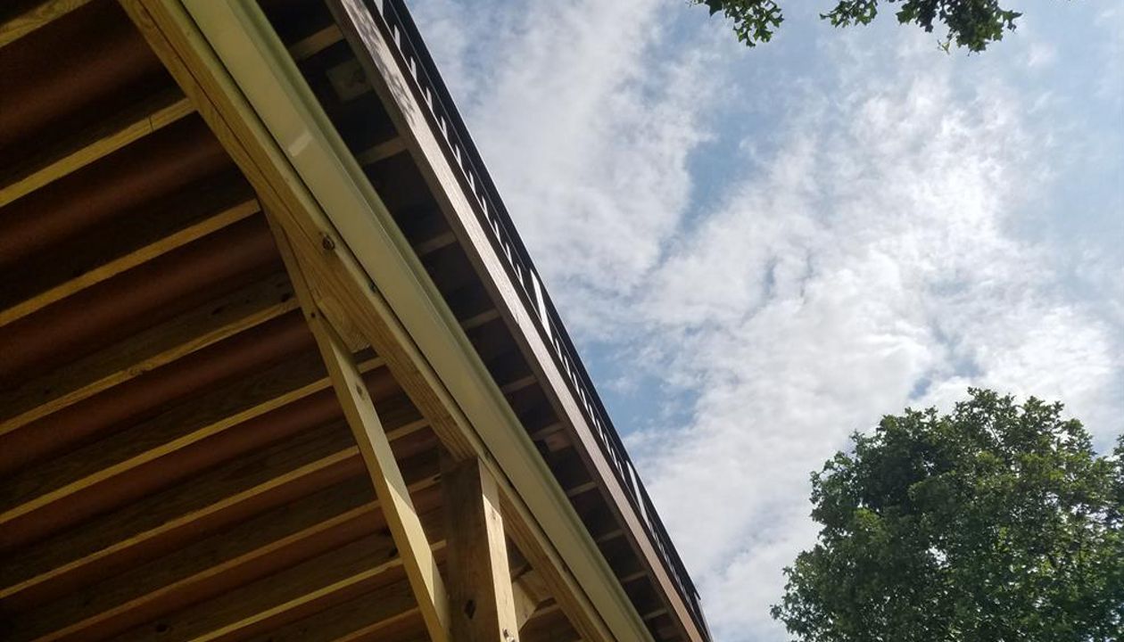 Trex RainEscape System with an open ceiling. The channels have a red/brown color and can be seen from underneath the deck.