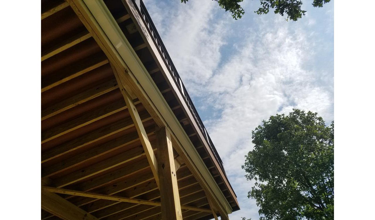 Trex RainEscape System with an open ceiling. The channels have a red/brown color and can be seen from underneath the deck.