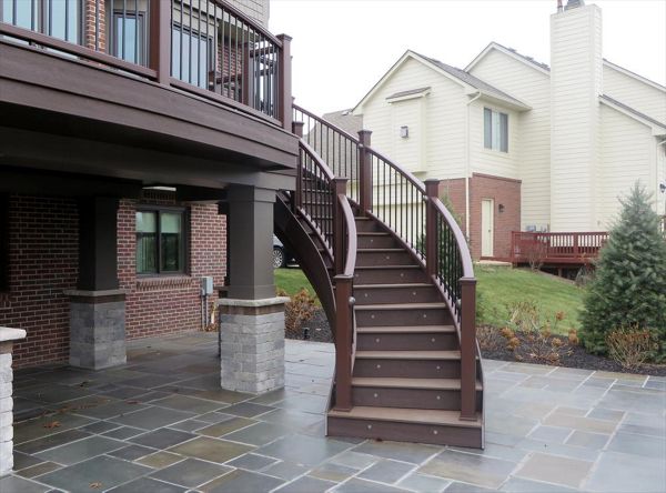 This deck in Plymouth, MI has fire pit Trex transcends decking with a vintage lantern border. The custom curve rail and stairs make this deck stand out.
