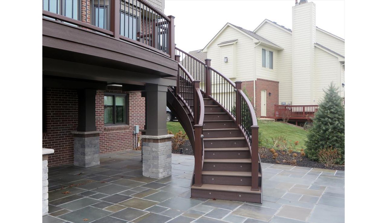 This deck in Plymouth, MI has fire pit Trex transcends decking with a vintage lantern border. The custom curve rail and stairs make this deck stand out.