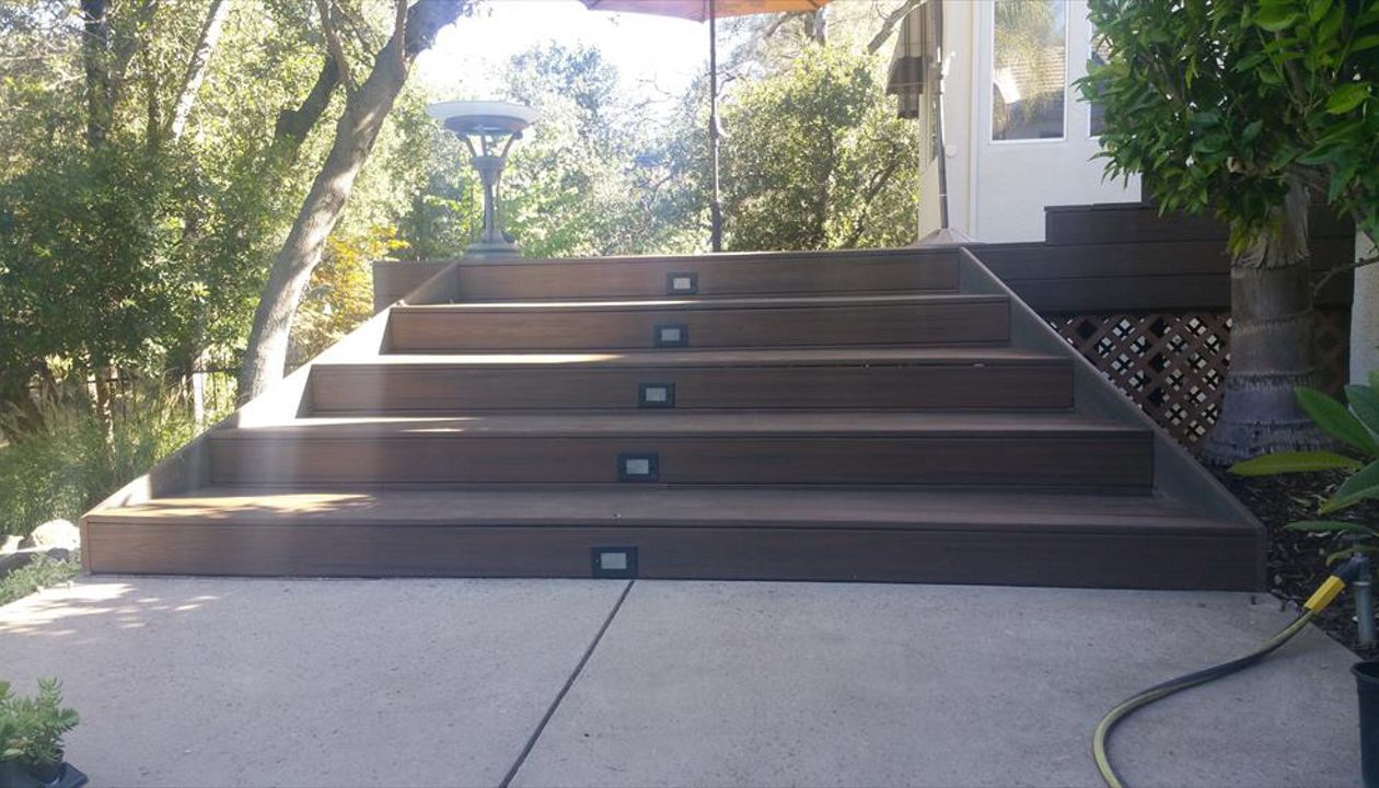 Custom Trex deck in Tiki Torch and Spiced Rum in Redding. Stairs have lighting and unique angles set to match the house. Majestic Builders is proud to provide top quality composite decks that will last a lifetime.