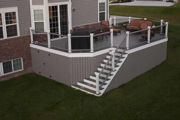 Trex Transcend Gravel Path Decking with white trim. Trex Transcend vertical skirting with door for storage. Trex Transcend gravel path railing with low voltage led cap lights.
