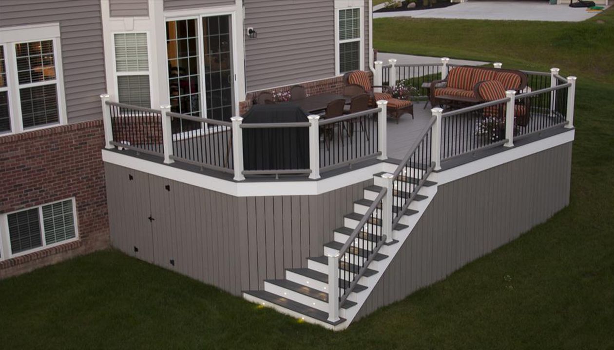 Trex Transcend Gravel Path Decking with white trim. Trex Transcend vertical skirting with door for storage. Trex Transcend gravel path railing with low voltage led cap lights.