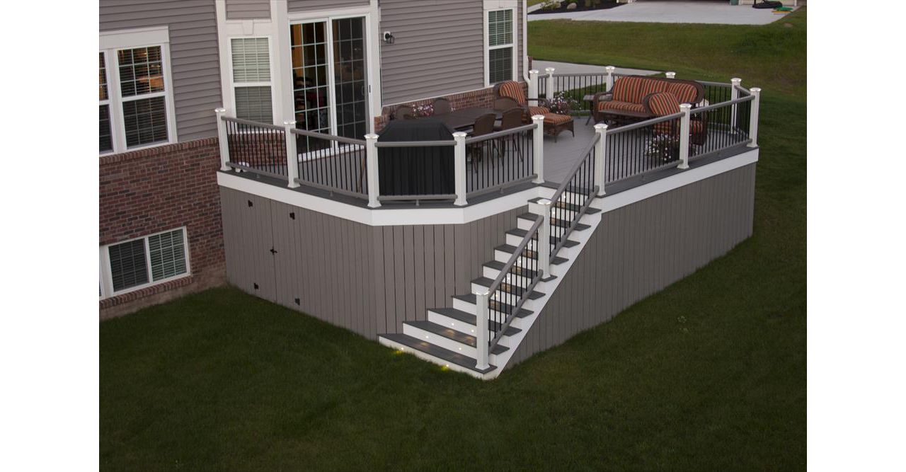 Trex Transcend Gravel Path Decking with white trim. Trex Transcend vertical skirting with door for storage. Trex Transcend gravel path railing with low voltage led cap lights.