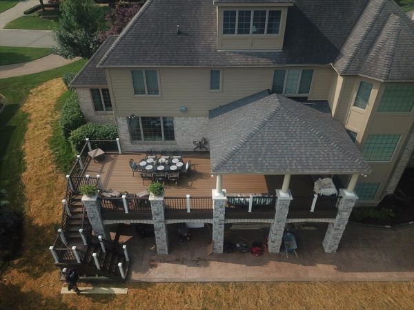 This deck located in Howell, MI has a custom roof structure. The deck is composed of Trex transcends havana gold and has a spiced rum border. The vintage lantern and white railing is Trex transcends as well. The brick columns make this deck one of a kind.
