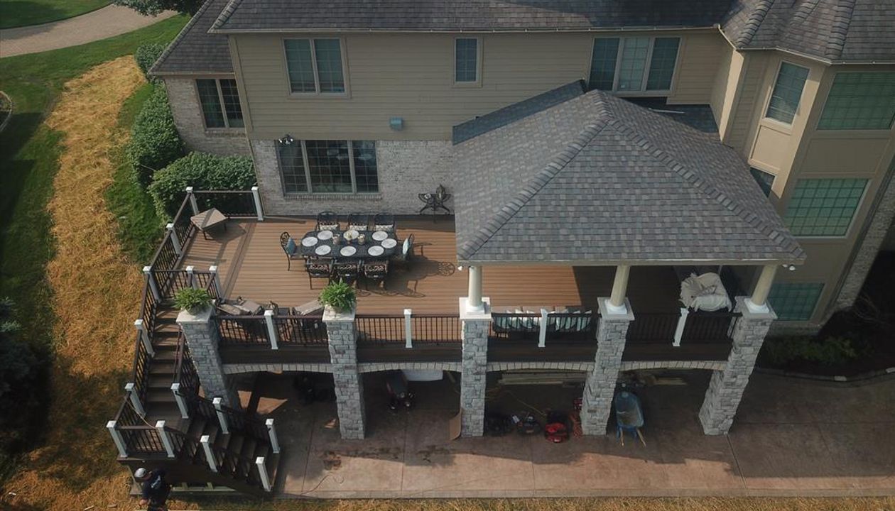 This deck located in Howell, MI has a custom roof structure. The deck is composed of Trex transcends havana gold and has a spiced rum border. The vintage lantern and white railing is Trex transcends as well. The brick columns make this deck one of a kind.