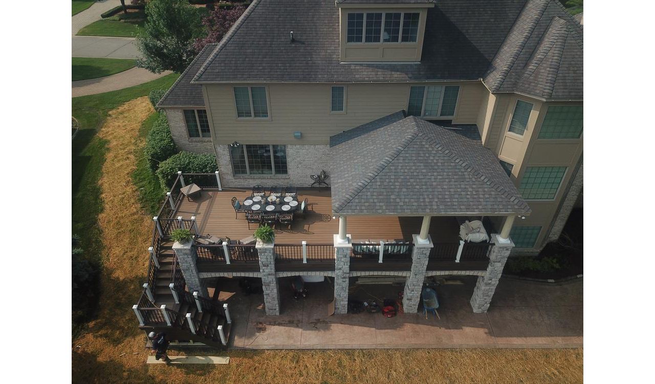 This deck located in Howell, MI has a custom roof structure. The deck is composed of Trex transcends havana gold and has a spiced rum border. The vintage lantern and white railing is Trex transcends as well. The brick columns make this deck one of a kind.