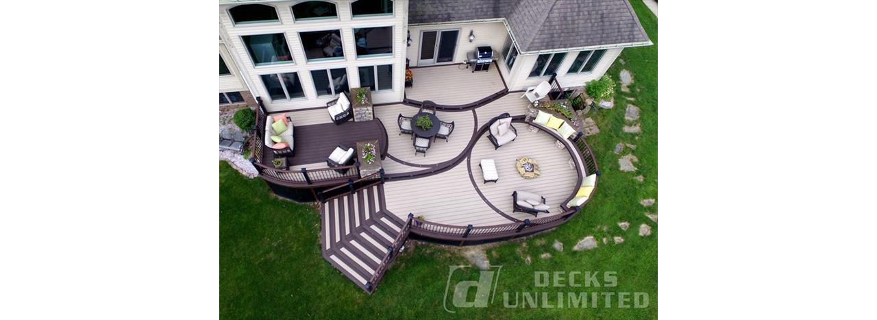 Show stopping TREX deck with all the main ingredients; curves, lighting, firepit, built in seating & planters, stone work, under deck storage, multi-levels, and flared staircase.