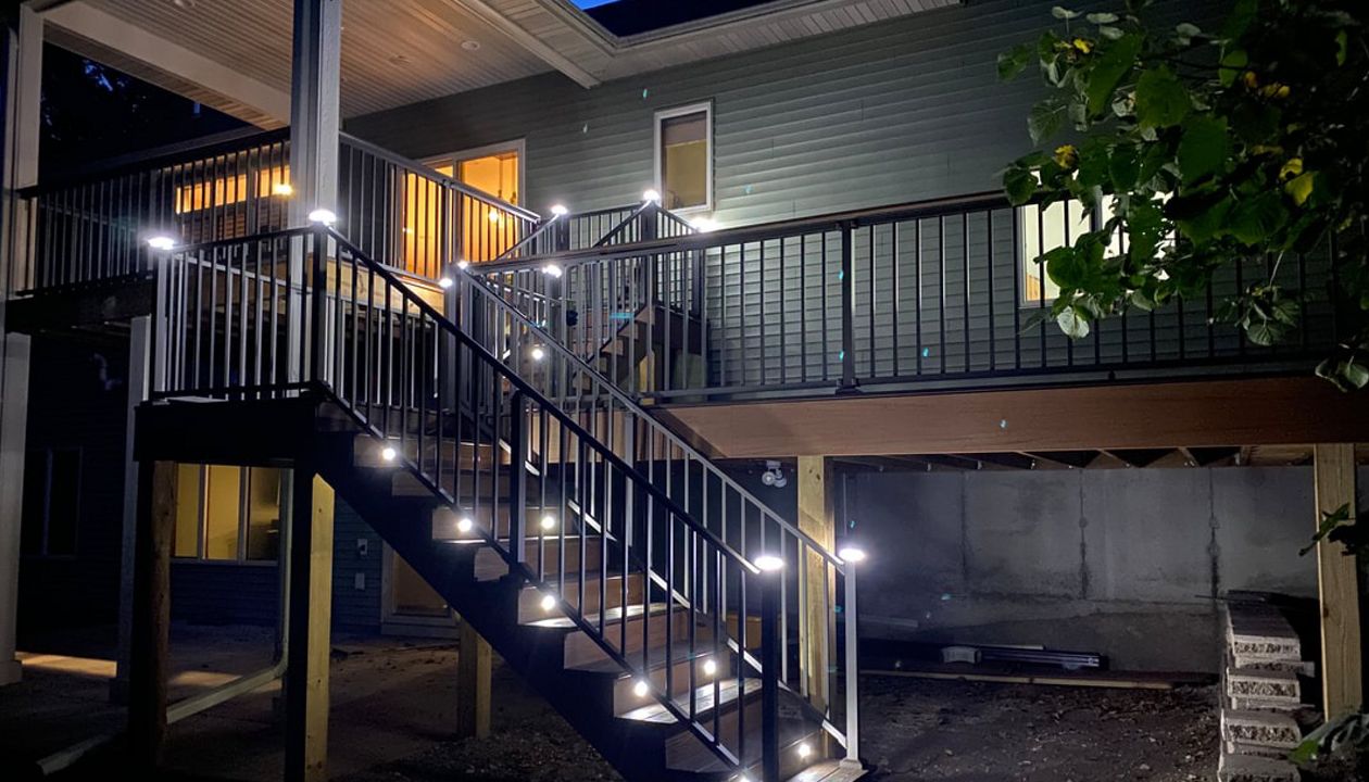 Two-Tone Low-Maintenance Trex Transcend Composite Deck with Black, Aluminum Railing and Featuring Low-Voltage, LED Lighting for Safety and Ambiance in the Rochester, MN Area built by Schmidt Carpentry, LLC