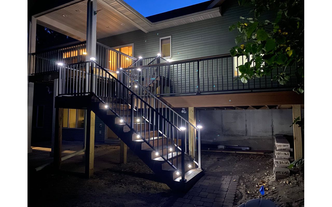 Two-Tone Low-Maintenance Trex Transcend Composite Deck with Black, Aluminum Railing and Featuring Low-Voltage, LED Lighting for Safety and Ambiance in the Rochester, MN Area built by Schmidt Carpentry, LLC