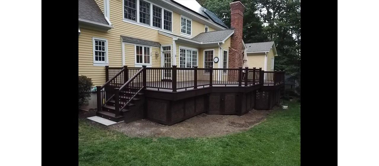Angled view of Trex Transcends Lava Rock Decking with Lighting in stair risers and post caps and Brazilian Walnut Vinyl Privacy lattice with Trex Transcends Lava Rock Decking Picture Frame