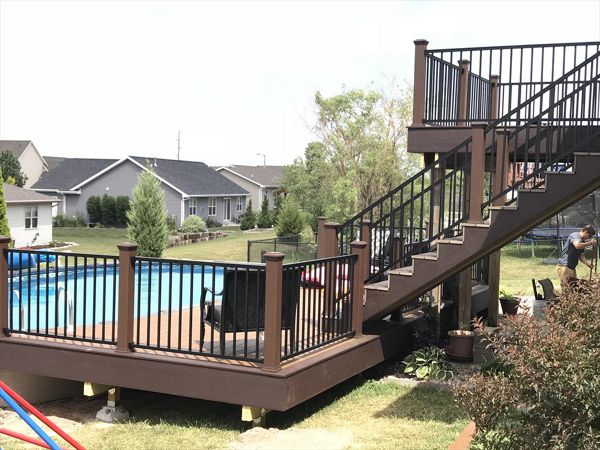 Customized decks done right by GE Contracting LLC. Vintage lantern rail posts with cap lights make the evenings much brighter for a swim. Signature black aluminum rails. Trex select Saddle inner boards and woodland brown accents. Make for a beautiful deck