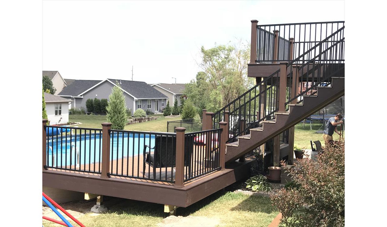 Customized decks done right by GE Contracting LLC. Vintage lantern rail posts with cap lights make the evenings much brighter for a swim. Signature black aluminum rails. Trex select Saddle inner boards and woodland brown accents. Make for a beautiful deck