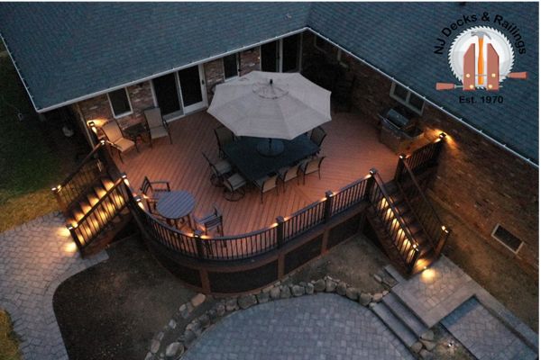 Curved deck with Tiki Torch decking, Lava Rock border and treads, Vintage Lantern railings with black aluminum balusters, post cap and riser lights