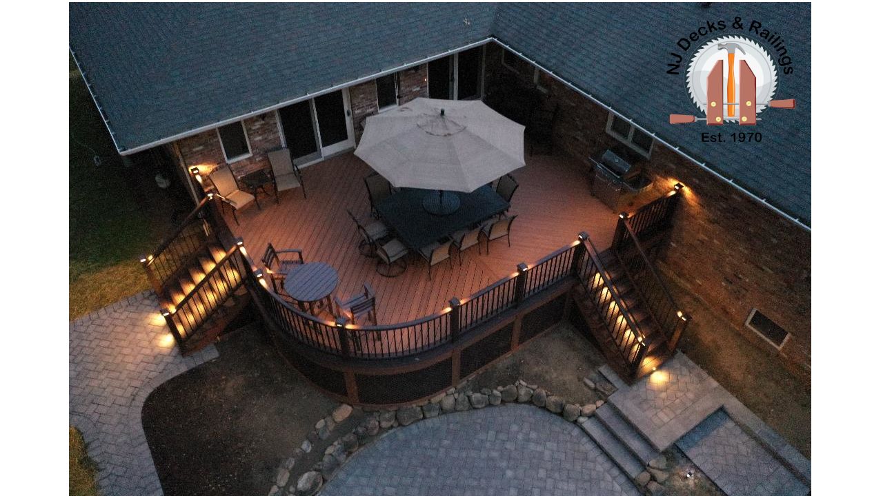 Curved deck with Tiki Torch decking, Lava Rock border and treads, Vintage Lantern railings with black aluminum balusters, post cap and riser lights