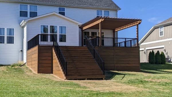 Trex Transcend Havana Gold with Signature railing in Charcoal Black. 12" Havana Gold skirting from ground up.Custom stained cedar Pergola.