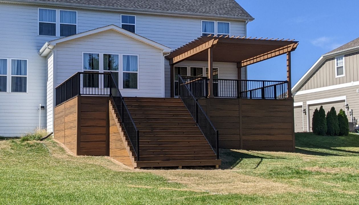 Trex Transcend Havana Gold with Signature railing in Charcoal Black. 12" Havana Gold skirting from ground up.Custom stained cedar Pergola.