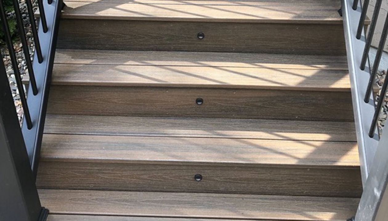 Trex/Transcend/Spiced Rum Composite Decking with Trex/Transcend Universal Composite Railing (black with round aluminum balusters) and Trex/Transcend Spiced Rum Composite Decking with Trex Stair Accent Lighting