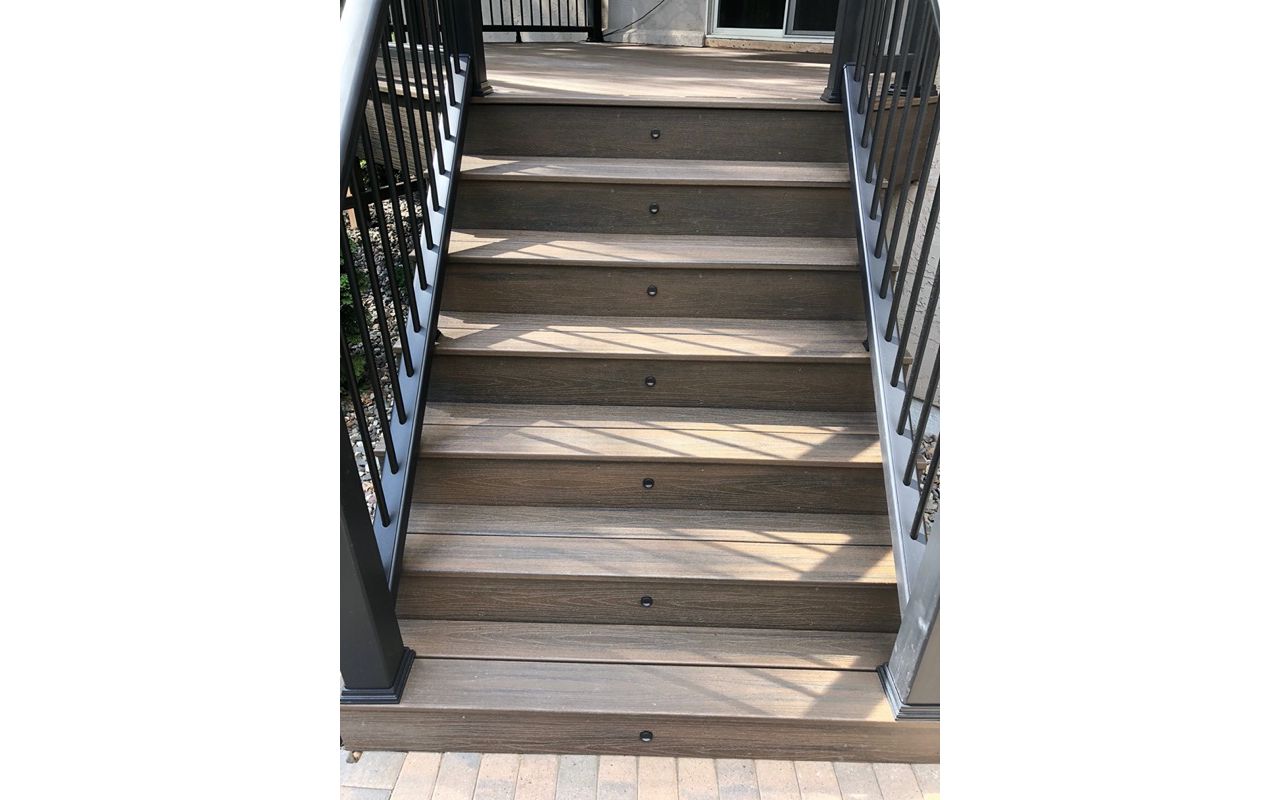 Trex/Transcend/Spiced Rum Composite Decking with Trex/Transcend Universal Composite Railing (black with round aluminum balusters) and Trex/Transcend Spiced Rum Composite Decking with Trex Stair Accent Lighting