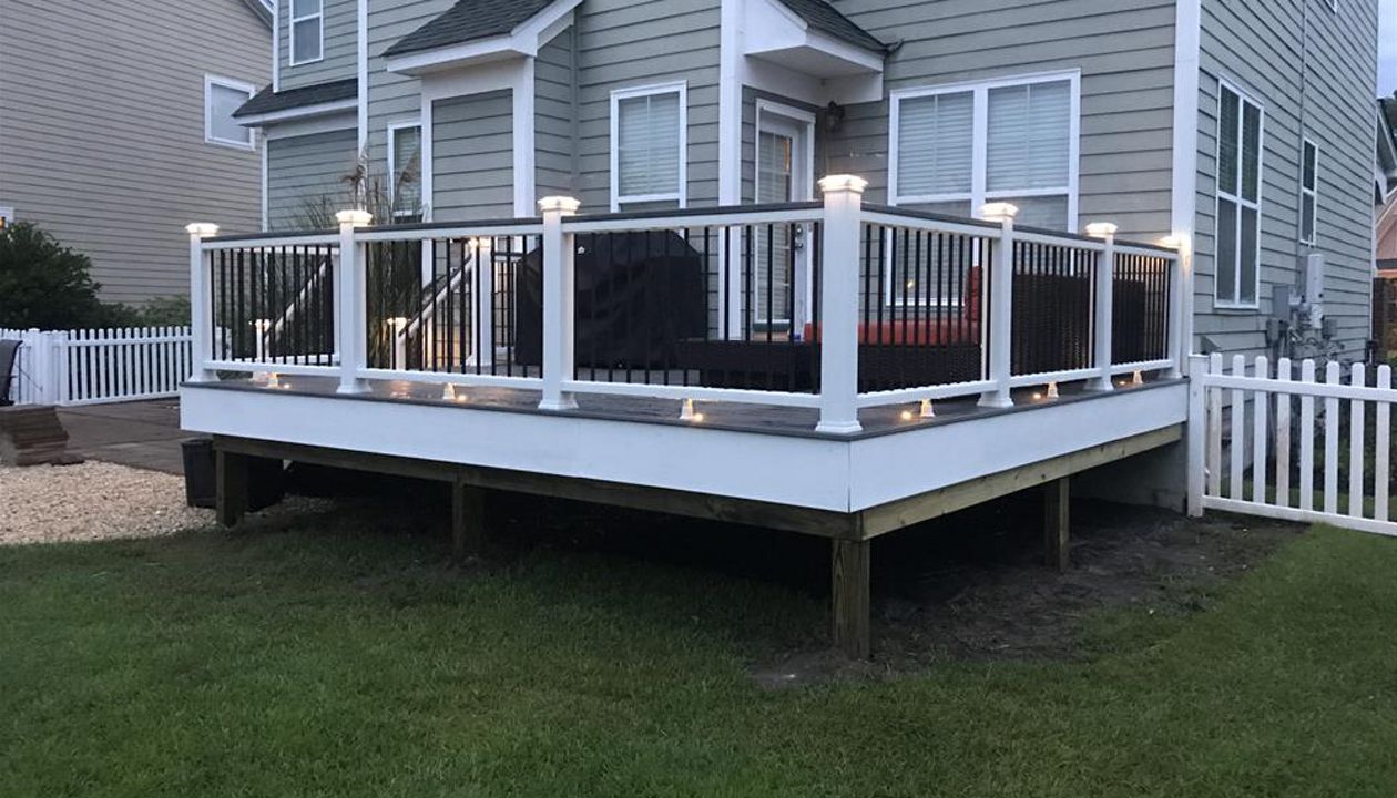 Trex Island Mist, universal rail with Trex Rail top, Black round balusters, cap lights, up lights, riser lights