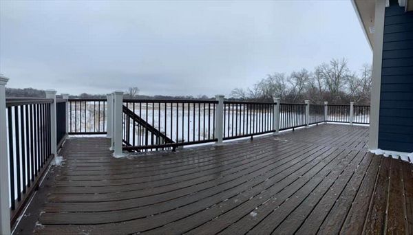 This deck features Trex transcend spiced rum decking and vintage lantern picture frame. Vintage lantern Top/bottom rail, white post sleeves, and black square aluminum ballasts.