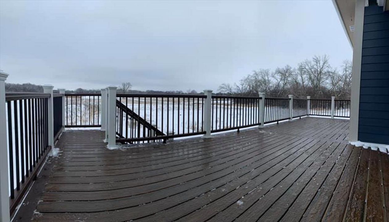 This deck features Trex transcend spiced rum decking and vintage lantern picture frame. Vintage lantern Top/bottom rail, white post sleeves, and black square aluminum ballasts.