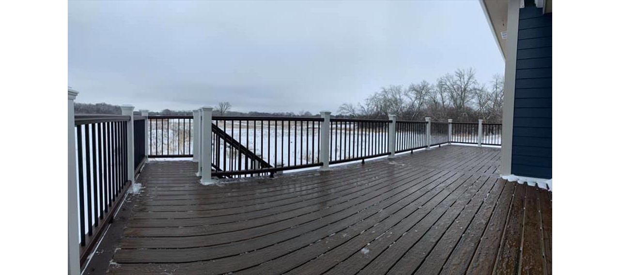 This deck features Trex transcend spiced rum decking and vintage lantern picture frame. Vintage lantern Top/bottom rail, white post sleeves, and black square aluminum ballasts.