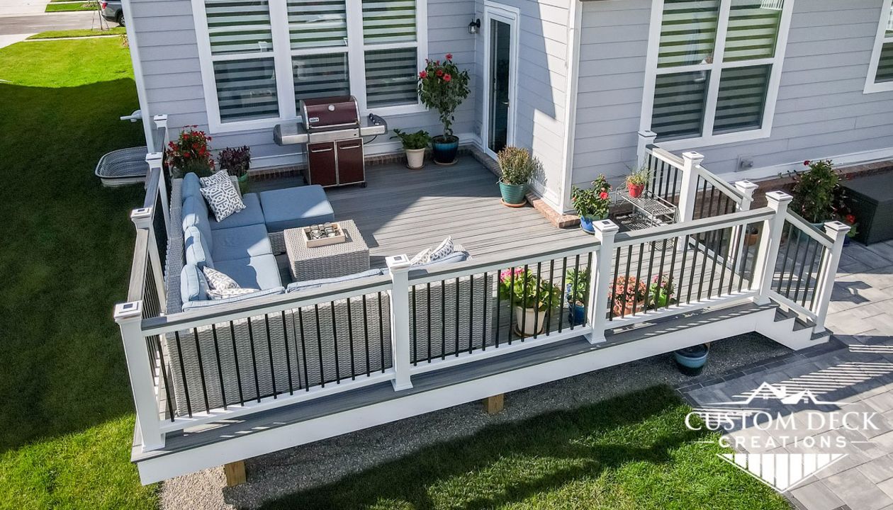 Trex Transcend Island Mist decking built with Trex Signature aluminum railing in black and white Trex composite railing posts. Matching cocktail board added to railing. Solar powered railing post cap lights.